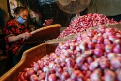 Seorang pekerja mengenakan masker wajah memilah bawang di pasar tradisional di tengah pandemi virus corona (Covid-19) di Jakarta, 3 Agustus 2020. (Foto: Reuters)