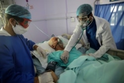 Medical workers attend to a COVID-19 patient in an intensive care unit at a hospital in Sanaa, Yemen, June 14, 2020.