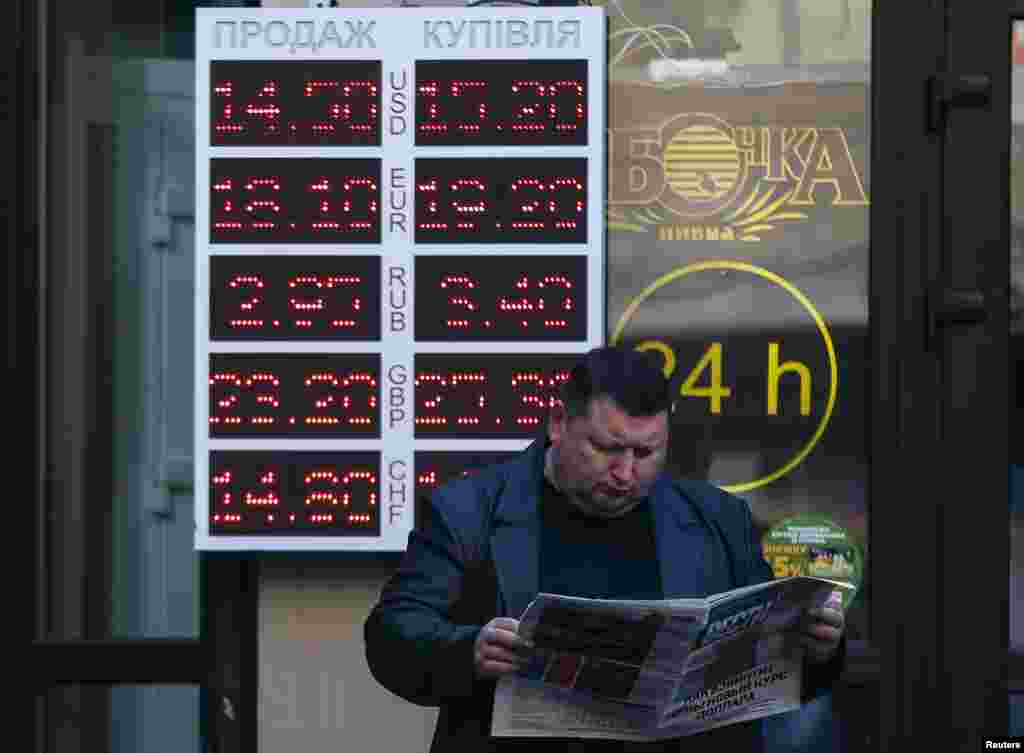 A man reads a newspaper near a currency exchange office in Kyiv. Ukraine's central bank said it believed the faltering hryvnia currency had fallen to an historic low, Nov. 10, 2014.