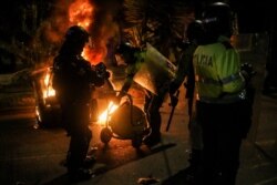 Agentes de policía intentan apagar el fuego de un contenedor de basura en llamas durante una protesta después de que un hombre, que fue detenido por violar las reglas de distanciamiento social, muriera por ser golpeado varias veces con una pistola.