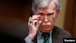 FILE - National Security Adviser John Bolton adjusts his glasses during a meeting in the Oval Office at the White House in Washington, April 2, 2019.