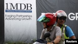 FILE - Motorcyclists pass a 1Malaysia Development Berhad (1MDB) billboard at the Tun Razak Exchange development in Kuala Lumpur, Malaysia, Feb. 3, 2016.