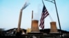 FILE - The U.S. flag flies on towboat M.K. McNally as it passes Mitchell Power Plant, a coal-fired power plant operated by American Electric Power, on the Ohio River in Moundsville, West Virginia, Sept. 10, 2017. 