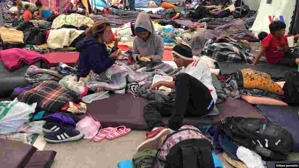 Los migrantes de Centro América se encuentran en un alburgue en Tijuana. En esta imagen se aprecia personas compartiendo alimentos en el piso. Fotografía: Celia Mendoza- VOA