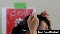 Un agent de santé enlève un masque de protection dans le service de soins intensifs pour les patients atteints de COVID-19 à l'hôpital universitaire St. Marianna à Kawasaki, au Japon, le 4 mai 2020.