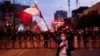 A protestor waves a Peruvian flag as police officers stand guard during a protest demanding the dissolution of Congress and to hold democratic elections rather than recognize Dina Boluarte as Peru's President, in Lima, Peru Dec. 11, 2022. 