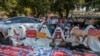 FILE - Hooded demonstrators display placards accusing China of supporting Myanmar's military during a protest against the recent coup, outside the Chinese Embassy in Yangon, Myanmar, Feb. 11, 2021.