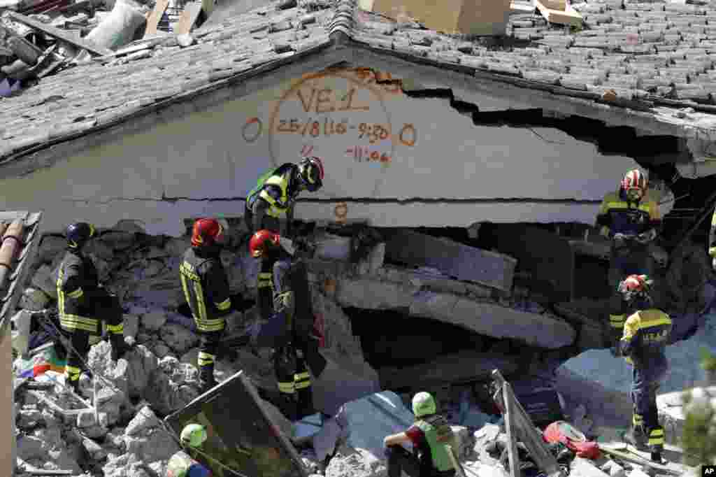 Rescuers mark a building with paint signaling the date and time of start and end of the search operation on that building, following Wednesday's earthquake in Pescara Del Tronto, Italy, Aug. 25, 2016.