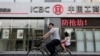 中国工商银行在北京的一家门市部门前，有提示“防抢劫”，一名男子带着女儿骑自行车经过（2013年6月26日）。