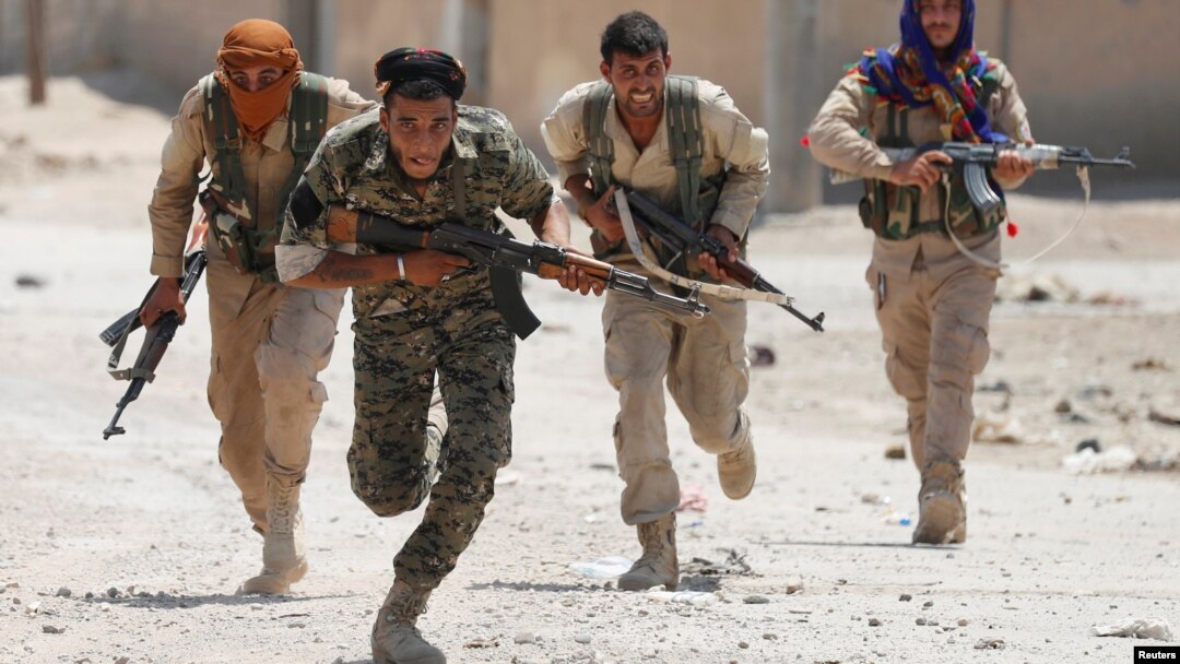 Kurdish fighters from the People's Protection Units (YPG) run across a street in Raqqa, Syria, July 3, 2017. 