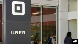 People make their way into the building that houses the headquarters of Uber, June 21, 2017, in San Francisco.