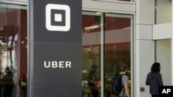 FILE - People make their way into the building that houses the headquarters of Uber, June 21, 2017, in San Francisco.