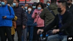 Residentes con mascarilla esperan en fila para someterse a una prueba rutinaria de detección del COVID-19, en Beijing, el 25 de octubre de 2022. (AP Foto/Andy Wong)