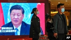 A security personnel checks a journalist near a TV screen showing image of President Xi Jinping at a media hotel in Beijing, Oct. 21, 2022.