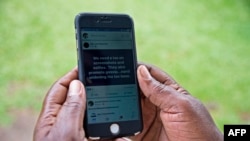FILE - A woman reads a message on social media on her phone in Kampala, Uganda, July 5, 2018. Activists say the vague wording in a social media usage law signed Oct. 13, 2022, will be used to silence government critics. 