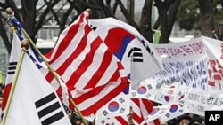 South Korean activists cheer as they wave flags of the United States and South Korea to celebrate the free trade agreement, or FTA, with the United States during a rally near the U.S. Embassy in Seoul, South Korea, March 14, 2012.