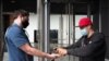 A Trader Joe's store employee, right, sprays hand sanitizer on a customer before he enters the Brooklyn supermarket, in New York, June 30, 2020.