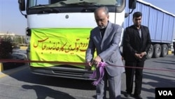 Kepala Badan Energi Atom Iran, Ali Akbar Salehi, memotong sebuah pita peresmian di fasilitas pengolahan uranium di Isfahan, dengan truk di belakangnya berisi bubuk uranium produksi dalam negeri Iran.