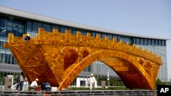 Workers install wires on a Golden Bridge of Silk Road structure on a platform outside the National Convention Center, the venue which will hold the Belt and Road Forum for International Cooperation, in Beijing, April 18, 2017.