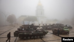 ARCHIVO - Un hombre pasa junto a vehículos militares rusos destruidos afuera del Monasterio de las Cúpulas Doradas de San Miguel en una mañana brumosa, en medio del ataque de Rusia a Ucrania, en Kiev, Ucrania, el 21 de octubre de 2023.