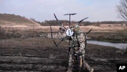 ARCHIVO - En esta foto tomada de un video publicado por el Servicio de Prensa del Ministerio de Defensa de Rusia el lunes 25 de marzo de 2024, un soldado ruso lleva un dron ucraniano capturado.