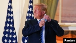 U.S. President Donald Trump pulls off his protective face mask as he poses atop the Truman Balcony of the White House after returning from being hospitalized at Walter Reed Medical Center for coronavirus disease (COVID-19) treatment, in Washington, Oct. 5, 2020 (REUTERS/Erin Scot
