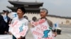People hold Korean Unification Flags during a pro-unification rally ahead of the upcoming summit between North and South Korea in Seoul, Apr. 26, 2018. The signs read, "Welcome inter-Korean summit" (L) and "Peaceful spring for our people" (R).