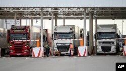 FILE - An employee of Eurotunnel and his dog check trucks on their way to Britain during a testing day in case of no-deal Brexit, at the exit of the Channel tunnel in Calais, northern France, Sept. 17, 2019. 