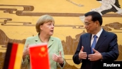German Chancellor Angela Merkel (L) chats with Chinese Premier Li Keqiang during the signing ceremony at the Great Hall of the People in Beijing, July 7, 2014.