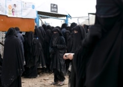 FILE - In this Tuesday, March 10, 2020 file photo, migrants wait in line for a distribution of blankets close to the Turkish-Greek border near Pazarkule, Edirne region, Turkey.
