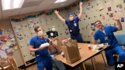 This photo provided by Brittney Caldera shows, from left to right, Oregon Health & Science University nurses Nick Greenwood, Callie Harling, Derrell Wheeler and Orion Meredith as they eat a meal delivered to the hospital's frontline COVID-19 health care workers in a break room.