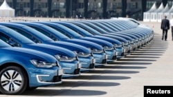 People walk past a row of Volkswagens during the company's annual news conference in Berlin March 13, 2014.