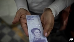 Una mujer muestra un nuevo billete de 500.000 bolívares después de retirarlo de un banco en Caracas, Venezuela, el 16 de marzo de 2021.