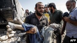 A Syrian carries the body of a child at the site of a reported regime airstrike on the village of Deir Sharqi on the eastern outskirts of Maaret al-Numan in Syria's northern province of Idlib, Aug. 17, 2019.