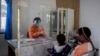 Seorang tenaga kesehatan berbicara dengan seorang perempuan dibalik pelindung plastik untuk mencegah penularan virus corona di sebuah puskesmas di Yalimo, Provinsi Papua, 21 April 2020. (Foto: AP)