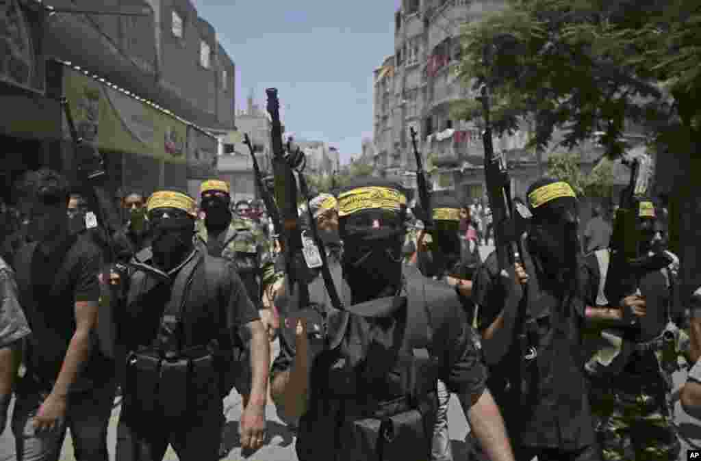 Niqobdagi qurollangan shaxslar Isroil hujumida halok bo'lgan "Fatah" guruhi ikki askarining dafn marosimida qatnashmoqda, 7-iyul, 2014-yil.