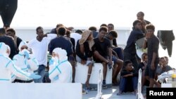 Para pengungsi menunggu untuk turun dari kapal di kapal penjaga pantai Italia "Diciotti" di pelabuhan Catania, Italia, 22 Agustus 2018.