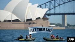 FILE - Members of the environmental group Greenpeace hold up a sign that reads "#LET THEM STAY" in front of the Opera House in Sydney, Australia, Feb. 14, 2016. 