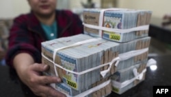 This photo taken on September 1, 2016 shows a banker with a stack of Myanmar kyat notes at the bank in Yangon. - Myanmar is spinning through a thrilling economic revival since shedding junta rule in 2011. But with an embryonic banking system - an estimate