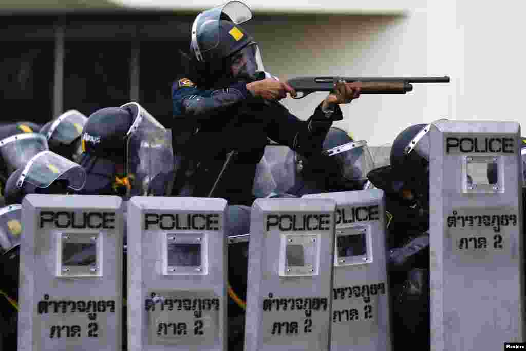 A policeman aims his weapon towards anti-government protesters during clashes near the Government House, Bangkok, Feb. 18, 2014.