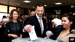 Foto yang dirilis di laman facebook Presiden Suriah ini menampilkan foto Presiden Bashar Assad didampingi istrinyam Asma (kiri), sedang memasukkan surat suaranya ke kotak suara dalam pemilu parlemem di Damaskus, Suriah (13/4). 