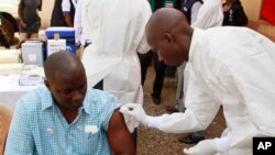 FILE - A health worker prepares to inject a man with an Ebola vaccine in Conakry, Guinea, March 7, 2015.