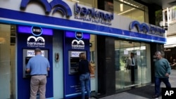 FILE - People use an ATM outside a bank, in Beirut, Lebanon, Nov. 20, 2019. 