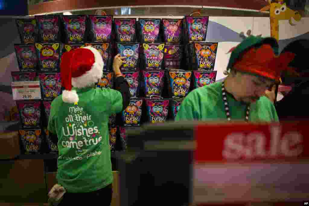 Para pegawai menyimpan persediaan boneka Furby di belakang kasir di toko Times Square Toys R' Us, New York (28/11). (AP/John Minchillo)