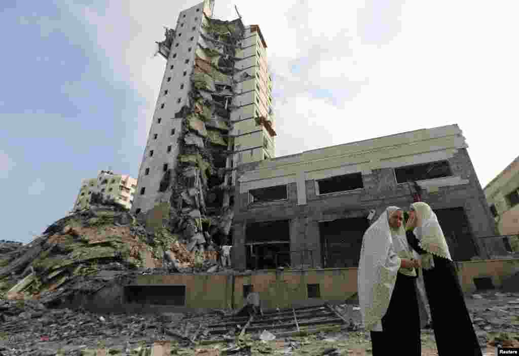 Palestinian women stand next to the remains of one of Gaza's tallest apartment towers, which was destroyed by an air strike, in Gaza City, Aug. 26, 2014.