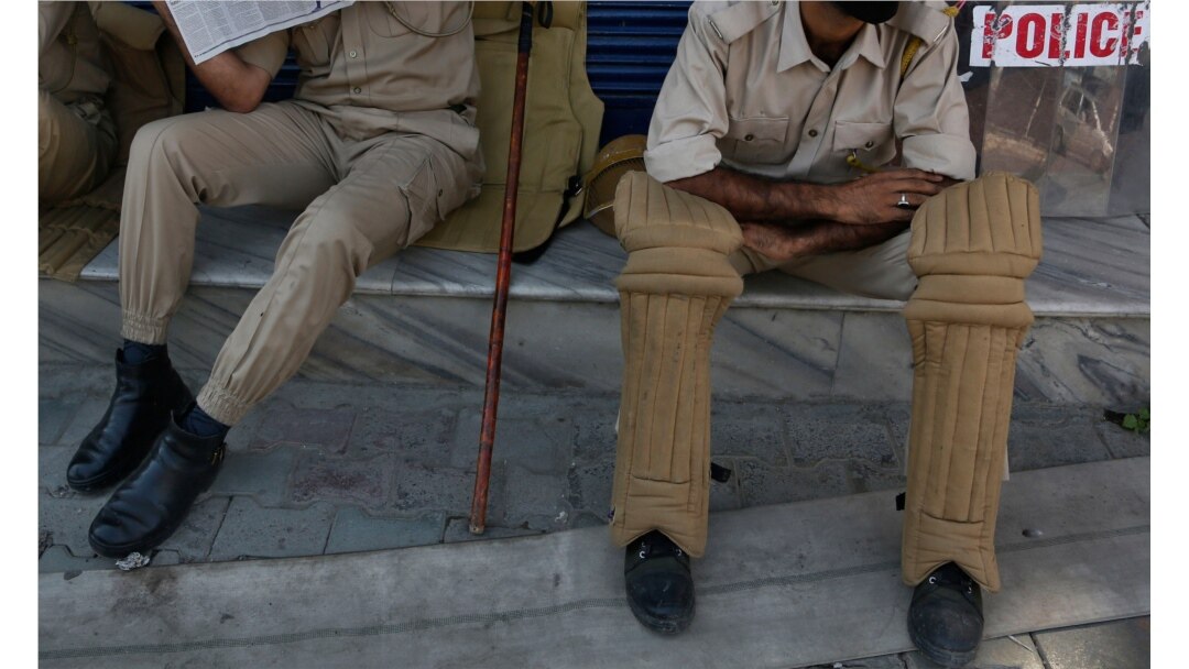Kashmiri policemen sit outside a closed shop in Srinagar, Indian-controlled Kashmir, Aug. 22, 2019.
