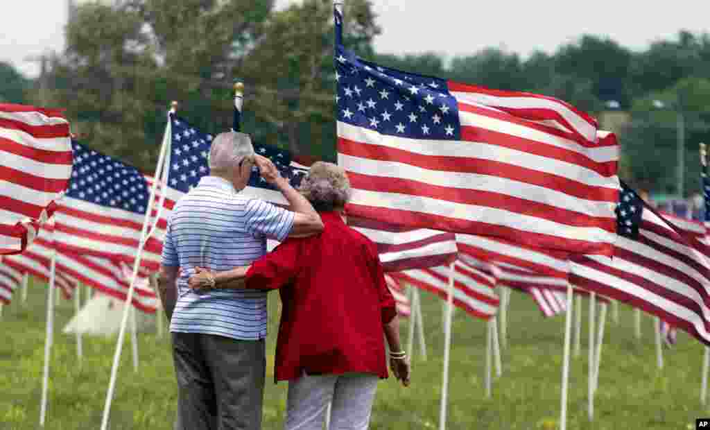 World War II veteran Jesse R. Turner salutes while being comforted by Helen Marie Misel at a display of more than 1700 United States flags in Shawnee, Kan., May 26, 2012.