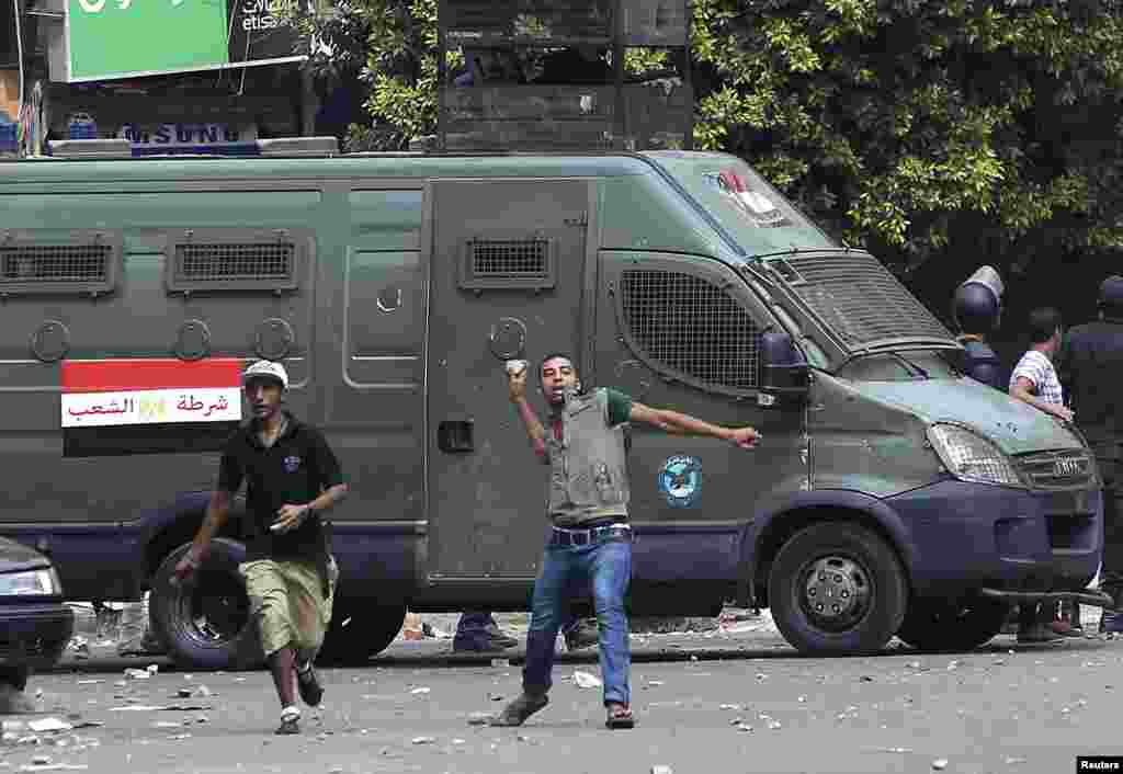 A local resident throws stones towards supporters of ousted President Mohamed Morsi during clashes in central Cairo, August 13, 2013.