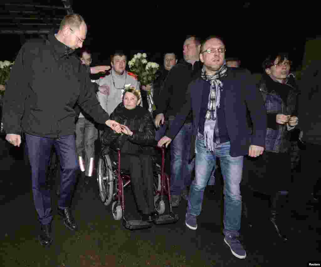 Ukrainian opposition leader Yulia Tymoshenko (C) is transported on a wheelchair upon her arrival at the airport in Kyiv, Feb. 22, 2014.