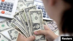 Seorang perempuan memegang uang kertas dolar AS dalam sebuah ilustrasi yang diambil pada 30 Mei 2022. (Foto: REUTERS/Dado Ruvic)